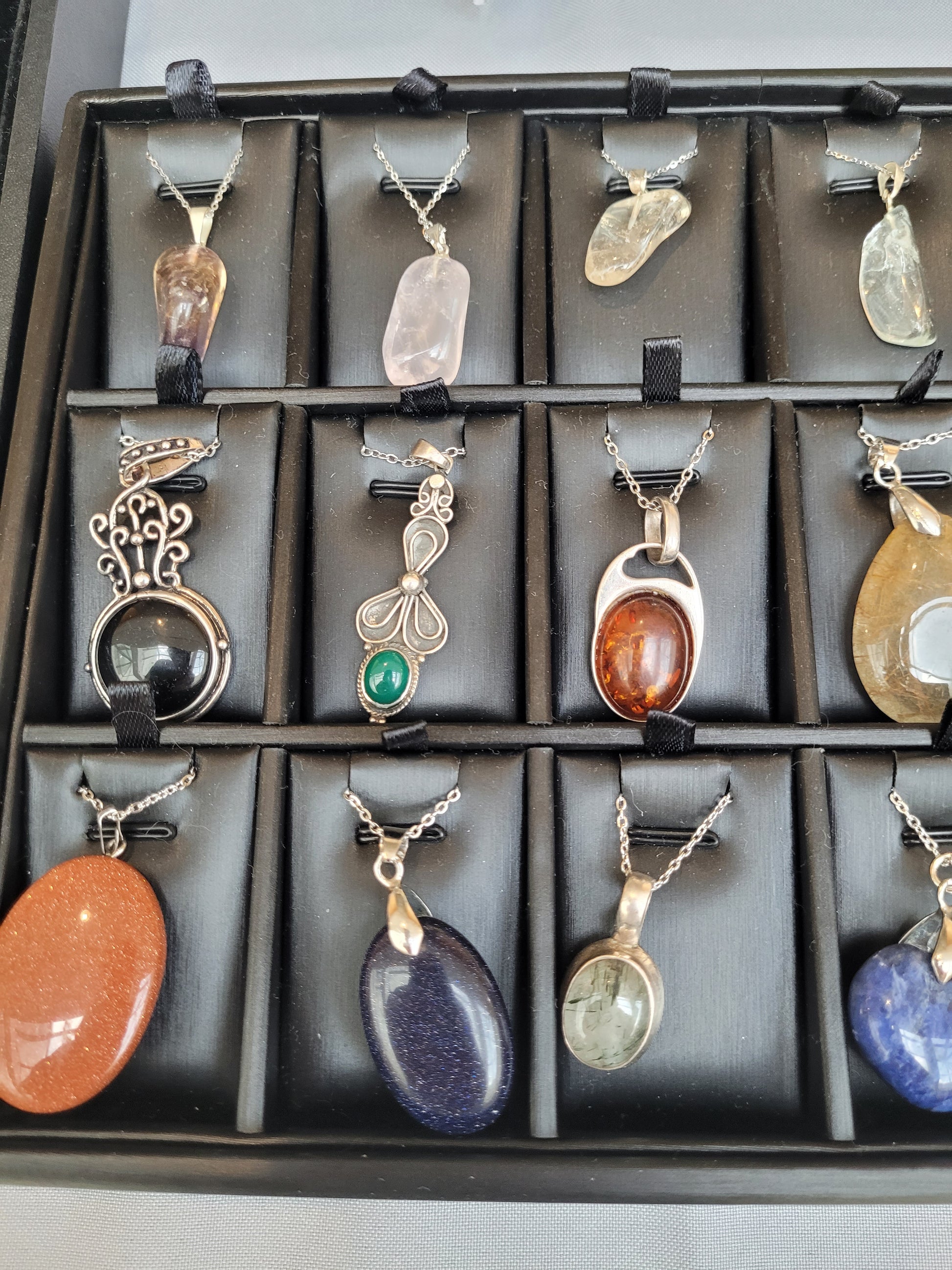 Collection of various pendants on a display tray with a neutral background