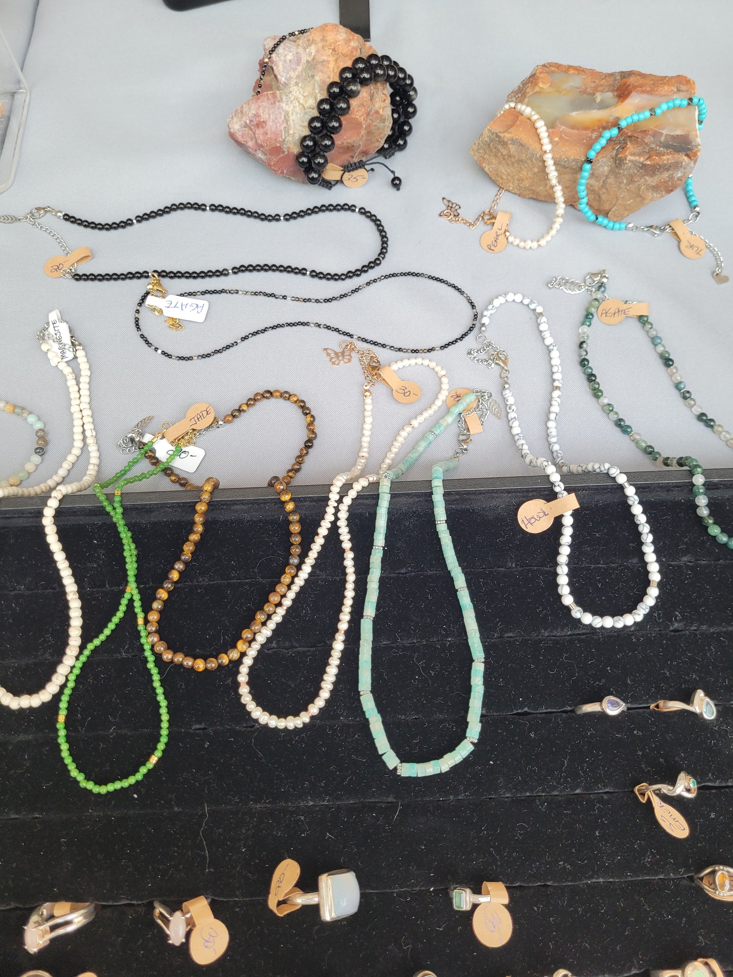 Collection of beaded necklaces and earrings on a white surface with a black background.