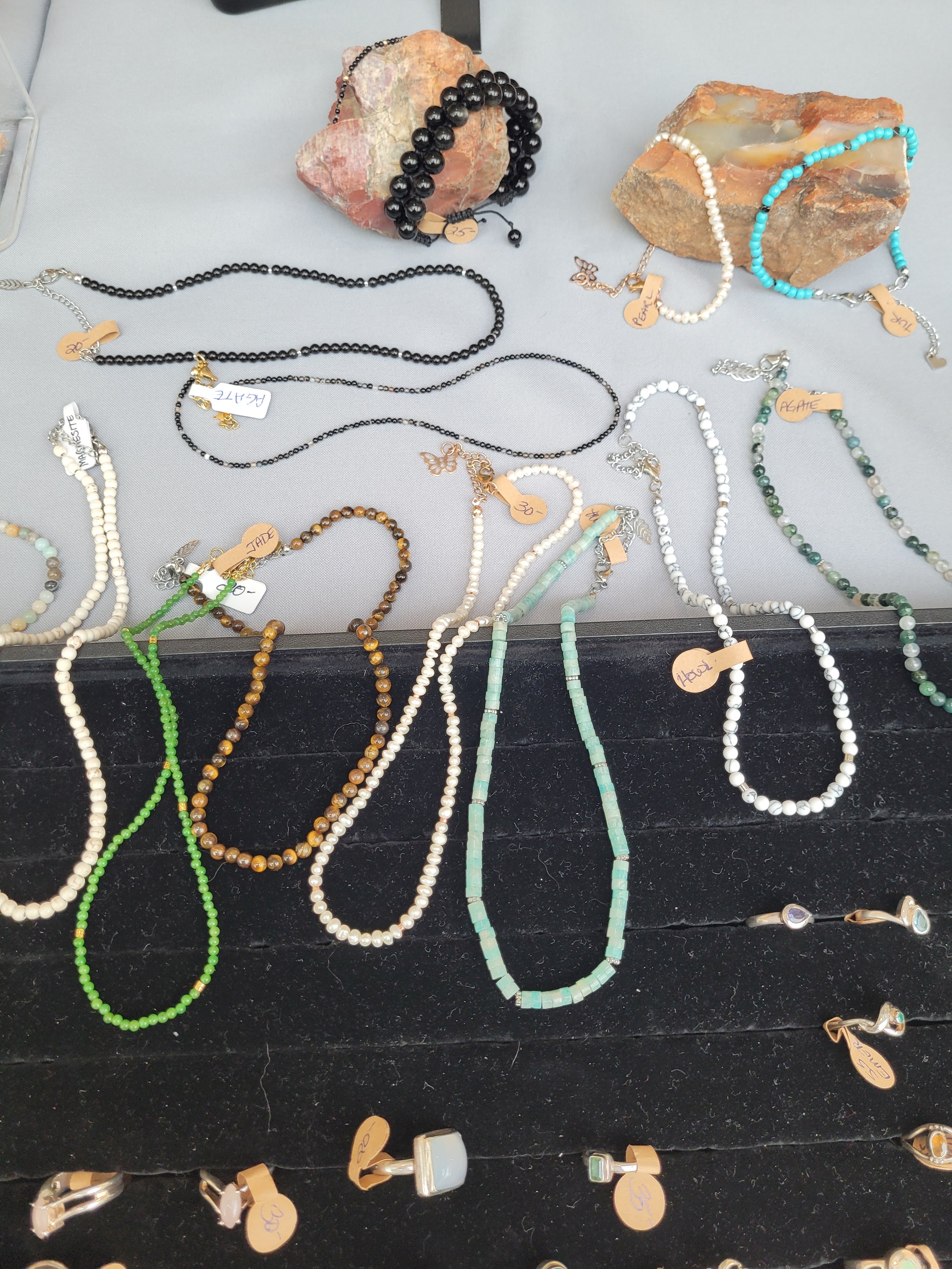 Collection of beaded necklaces and earrings on a white surface with a black background.