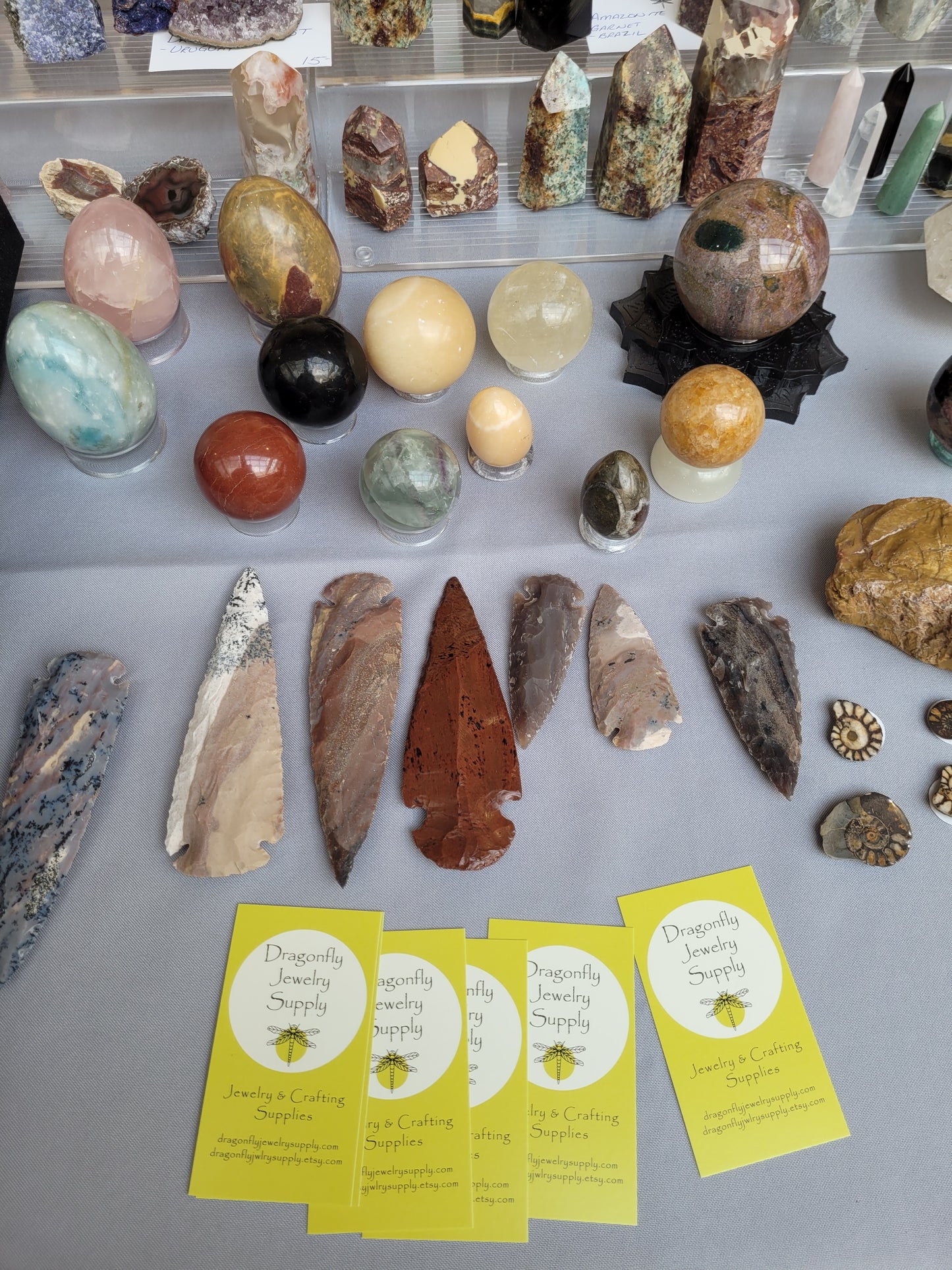 Collection of rocks, minerals, and arrowheads on a gray surface with business cards.