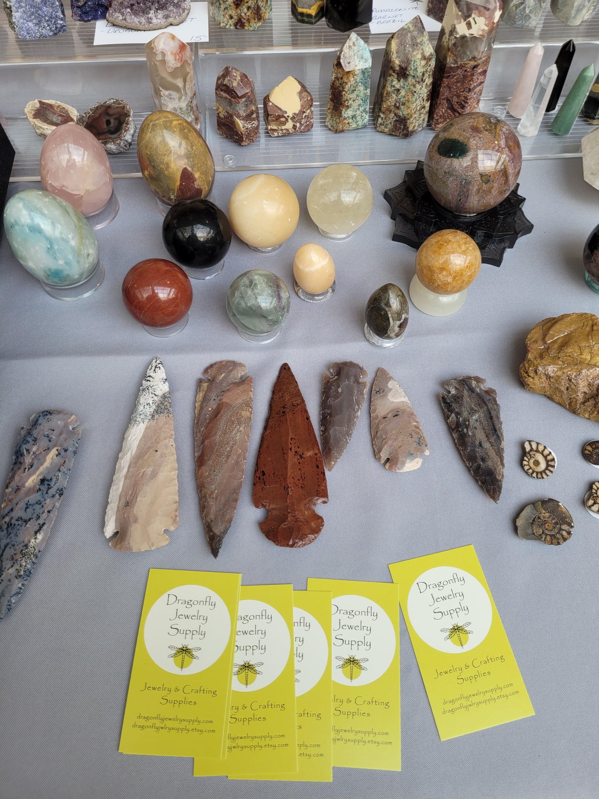 Collection of rocks, minerals, and arrowheads on a gray surface with business cards.