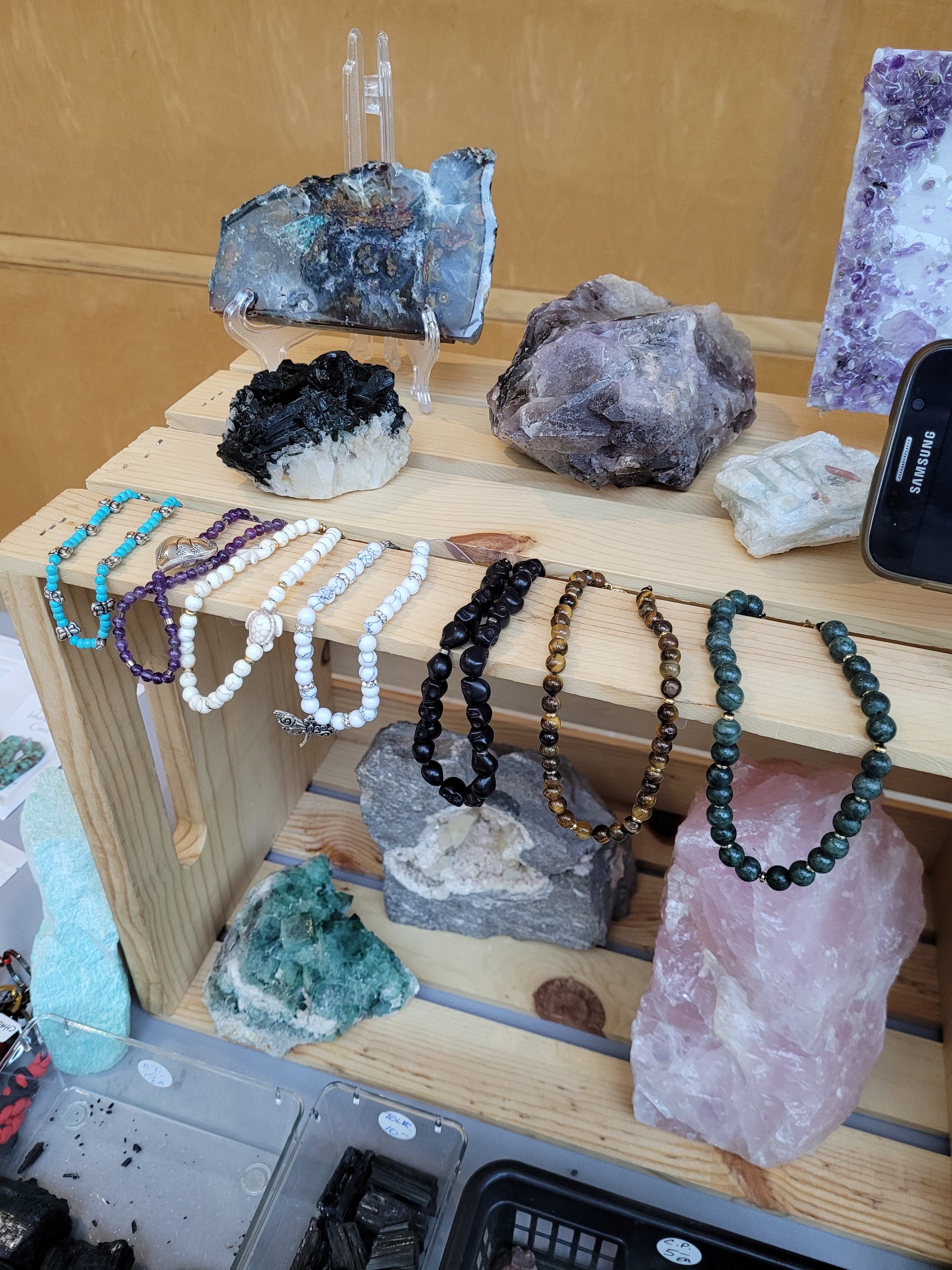 Jewelry displayed on a wooden stand with crystals and stones.