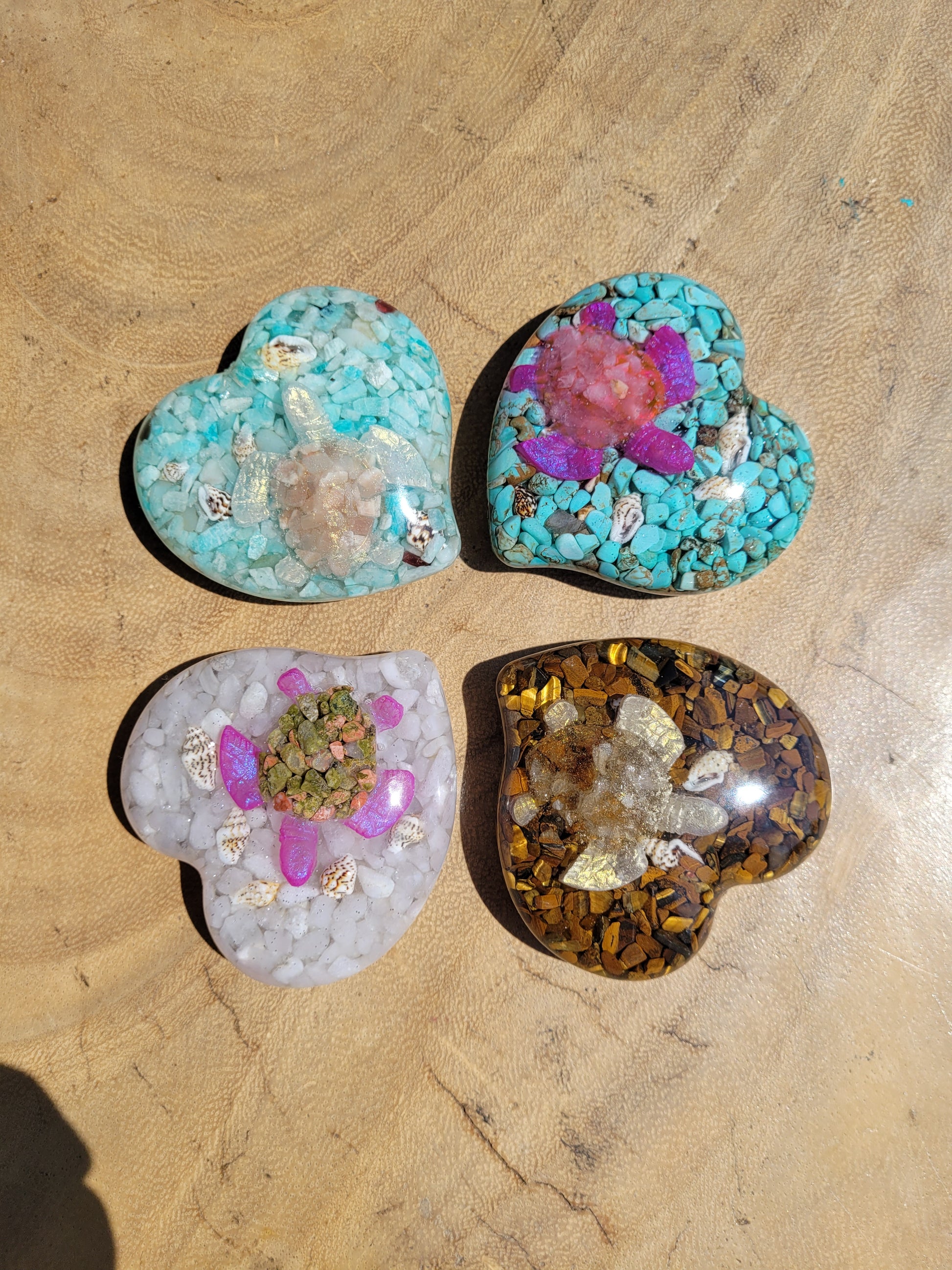 Four crystal and resin hearts with crystal turtles on a wooden surface